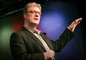 Middle-aged man passionately discussing creativity in education.