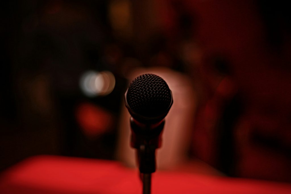 Close-up of a microphone on a dark stage with blurred lights in the background