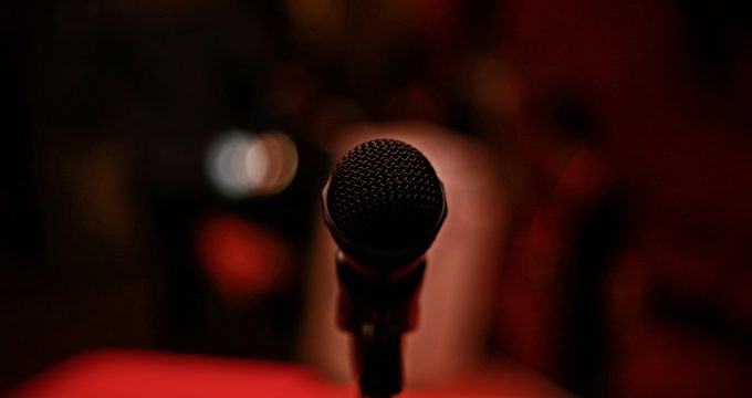 Close-up of a microphone on a dark stage with blurred lights in the background